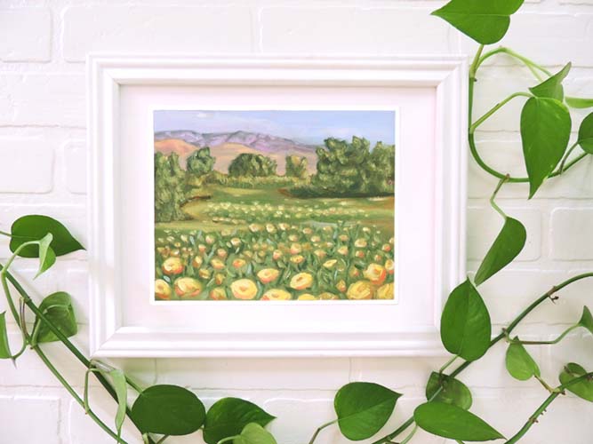 original landscape oil painting with mountains, trees, and yellow flowers in white frame.